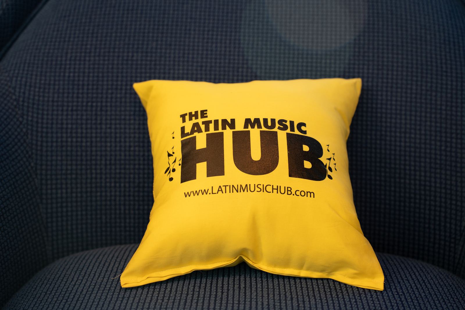 A yellow Latin Music Hub pillow on a lounge chair