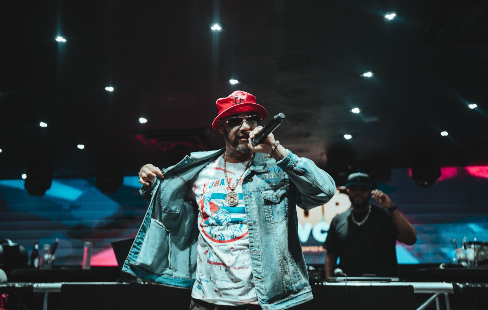 An artist performing in a red bucket hat and denim jacket at a Latin Music Hub showcase